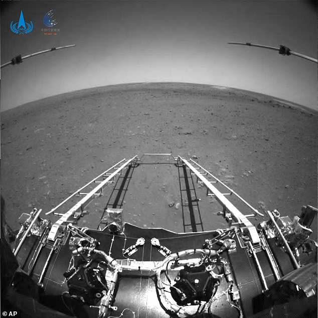 En esta toma frontal en blanco y negro tomada por el rover Zhurong Mars de China y puesta a disposición por la Administración Nacional del Espacio de China (CNSA) el miércoles, se despliegan brazos de extensión y una rampa de salida en el módulo de aterrizaje del rover en la superficie de Marte.