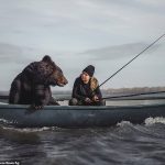 En la foto: Archie, un oso pardo rescatado, junto con su dueña Veronika Dichka pescando en un barco en Novosibirsk, Rusia.