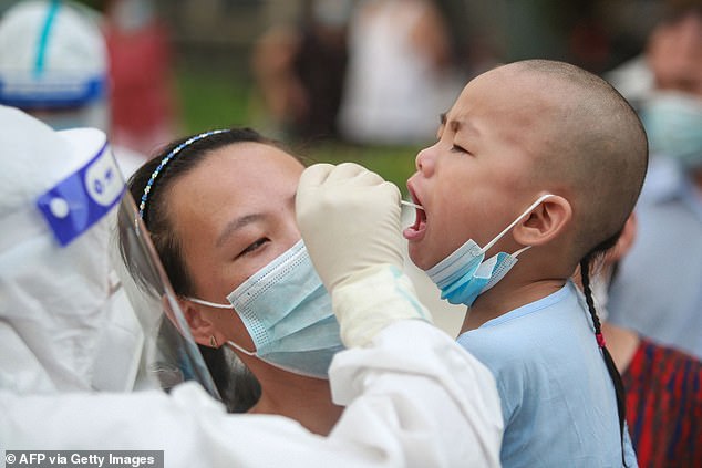 Un médico que usa equipo de protección personal completo hace un hisopado de un niño para detectar Covid en un centro de pruebas en Yangzhou, en la provincia de Jiangsu, en el este de China.  La ciudad había registrado 126 casos hasta el martes.