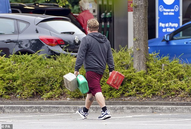 Un hombre que transportaba contenedores en una gasolinera Tesco en Bracknell, Berkshire, en medio de la escasez de conductores de vehículos pesados