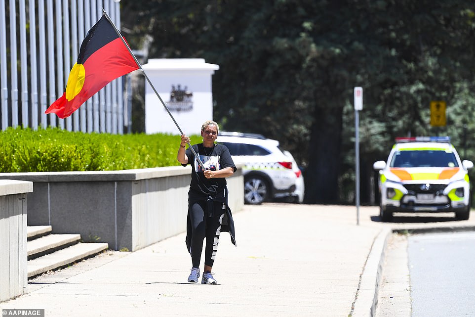 Un manifestante lleva la bandera aborigen frente a la antigua casa del parlamento en Canberra, el jueves 30 de diciembre de 2021