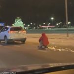 El hombre se agarra a las manijas del scooter y se pone en cuclillas mientras el SUV lo arrastra por la autopista helada en la ciudad de Voronezh, Rusia.