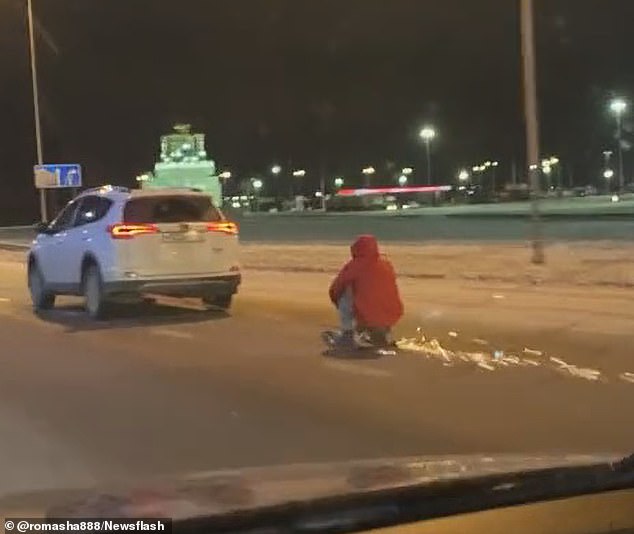 El hombre se agarra a las manijas del scooter y se pone en cuclillas mientras el SUV lo arrastra por la autopista helada en la ciudad de Voronezh, Rusia.