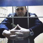 La policía rusa allanó las casas de dos aliados del crítico del Kremlin encarcelado Alexei Navalny, y uno de ellos enfrenta hasta 12 años de cárcel.  En la imagen: Navalny aparece en el tribunal de Petushinsky a través de un enlace de video en una audiencia sobre su demanda contra su colonia carcelaria que lo clasifica como una amenaza potencial extremista o terrorista.