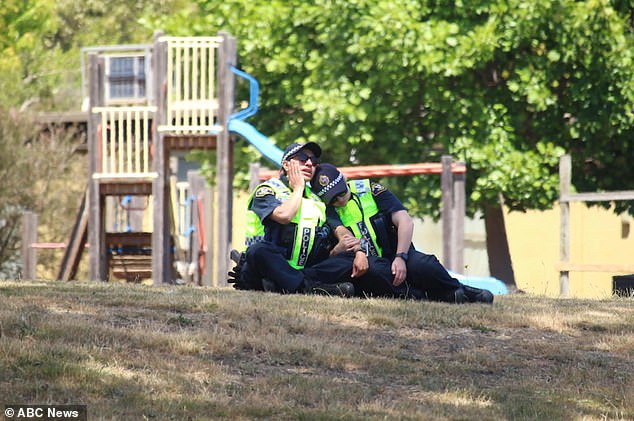 Dos policías se consuelan mutuamente en la escuela primaria Hillcrest, en Tasmania, después de que cuatro niños murieran cuando un castillo saltarín voló diez metros en el aire.