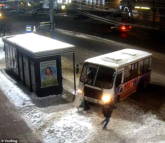 La mujer, que no parece darse cuenta de que el autobús está a punto de golpearla, cae en la nieve en Yaroslavl, Rusia.