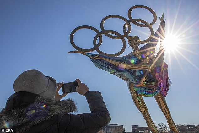 Una mujer toma fotos con su teléfono móvil de una escultura de patinaje artístico erigida para los Juegos Olímpicos de Invierno de Beijing 2022, en el Parque Industrial Shougang, que se utilizará como sede para albergar deportes y otros eventos durante los Juegos Olímpicos de Invierno de Beijing 2022