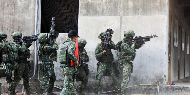 El jueves, soldados de dos pelotones en Taiwán se enfrentaron en una batalla simulada, disparándose desde casas y barricadas de sacos de arena mientras los tanques rodaban por una calle en una ciudad simulada con carteles de farmacias y marcas de cerveza.
