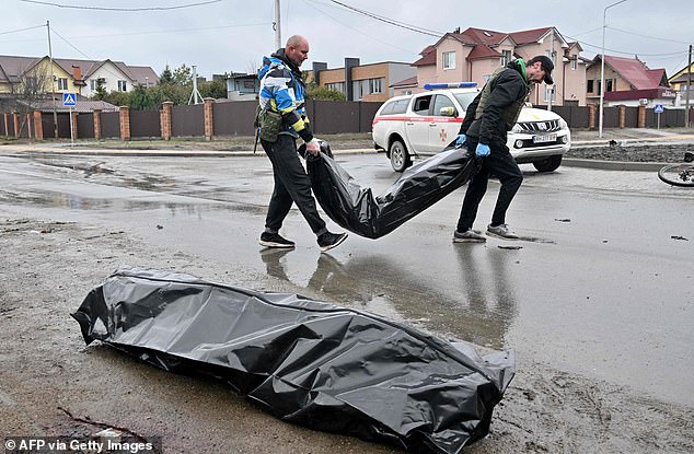 Los trabajadores comunales llevan bolsas para cadáveres en la ciudad de Bucha, no lejos de la capital ucraniana de Kiev el domingo.