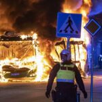 Un autobús arde mientras un oficial de policía observa los disturbios en Malmo, en el sur de Suecia, provocados por un político danés anti-islámico que realiza acrobacias para quemar el Corán en todo el país.