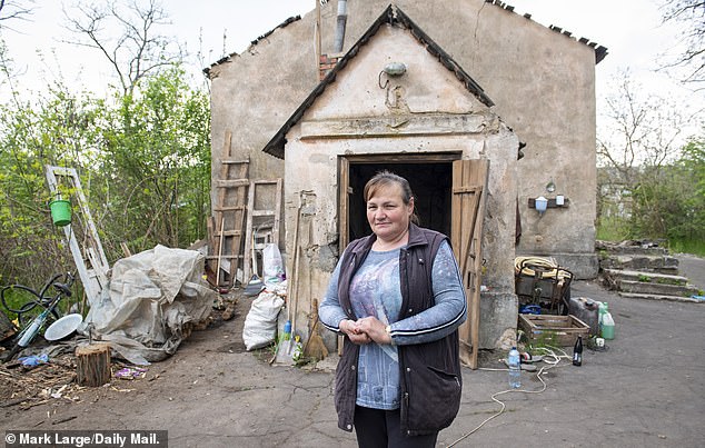 Svetlana Ginzhul, de 54 años, frente a su granero y la entrada a su refugio subterráneo, en Luch, donde ella y otros residentes van cuando el área es bombardeada.