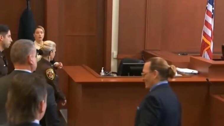 Johnny Depp sonríe y se encoge de hombros mientras Amber Heard retrocede torpemente para encontrarse cara a cara con él en la sala del tribunal.  Reloj