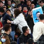 El activista Max Mok sostiene un cartel que exige la liberación del preso político uigur australiano Mirzat Taher en las gradas durante el partido de clasificación para la Copa Mundial entre Australia y China (en la foto)