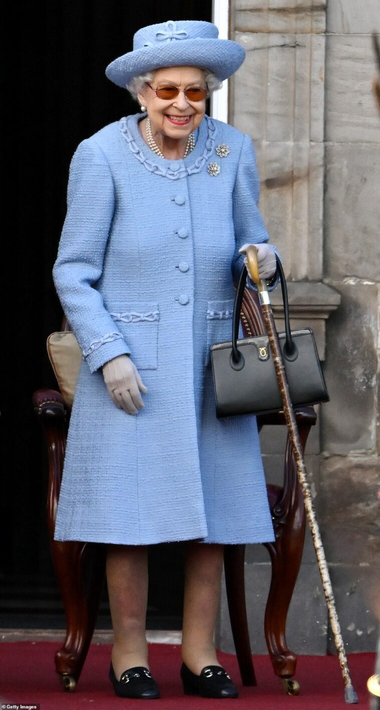 ¡Brillando en azul!  La Reina es toda sonrisas mientras asiste al Desfile de la Compañía Real de Arqueros Reddendo en los jardines del Palacio de Holyroodhouse.