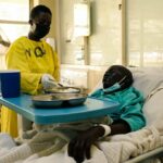 A nurse serves a meal to a patient lying on a bed in a medical ward at a local hospital in Harare on 26 April 2022.