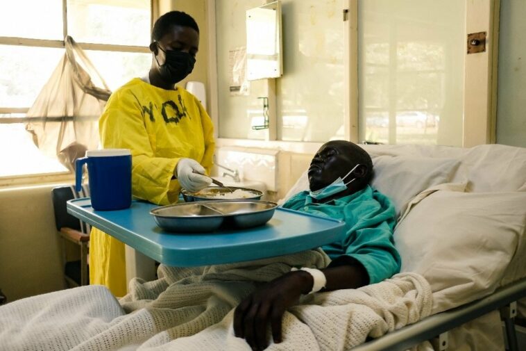 A nurse serves a meal to a patient lying on a bed in a medical ward at a local hospital in Harare on 26 April 2022.