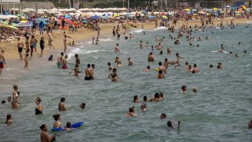 Los británicos que vayan de vacaciones de verano a Barcelona podrían ser multados por fumar en la playa.  En la imagen: la gente se refresca en el agua durante el clima cálido en una playa de Barcelona, ​​el 19 de junio.