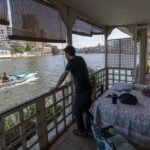 Un residente egipcio se encuentra en el balcón de su casa flotante, una comunidad ubicada en el distrito de Agouza en la orilla del río Nilo en Giza, el 27 de junio de 2022 (AFP)