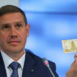 El vicegobernador del Banco de Rusia, Sergey Belov, sostiene el billete de 100 rublos rusos de nuevo diseño.  La Asociación de Bancos Rusos solicitó un retraso de seis meses en la introducción del nuevo billete de 100 rublos, ya que dijo que se necesitaba una nueva función de seguridad.