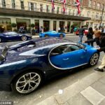 Un hombre recoge lo que se entiende como una multa del parabrisas de un Bugatti Chiron de 2,4 millones de libras fuera del exclusivo hotel de cinco estrellas May Fair en Londres.