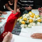Los dolientes iraquíes rezan sobre los ataúdes de una mujer y su sobrina asesinados en Zakho durante su funeral en Najaf el 21 de julio de 2022 (AFP)