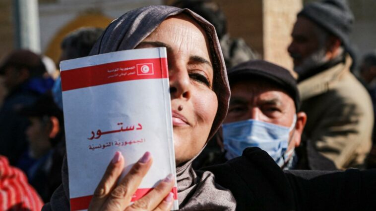 Una mujer sostiene una copia de la constitución tunecina durante una manifestación en Túnez contra los decretos del presidente Kais Saied el 13 de febrero de 2022.