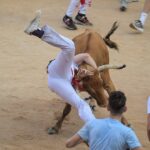 Un participante es levantado en el aire por un toro en el ruedo al final del curso cuando comenzó el famoso festival de San Fermín de Pamplona.