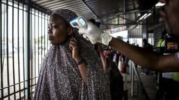 A woman gets her temperature measured at an Ebola screening station as she enters the Democratic Republic of the Congo from Rwanda on July 16, 2019 in Goma.
