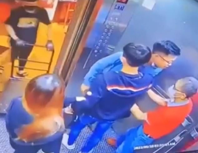 Hu, que vestía una camisa azul, comenzó a abordar a un anciano vestido de naranja después de que las puertas del ascensor se cerraran accidentalmente tras él.