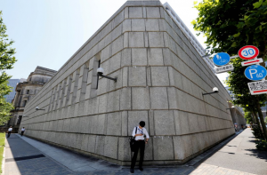 Un hombre mira un teléfono móvil frente al edificio del Banco de Japón en Tokio, Japón, el 16 de junio de 2017. (Reuters)