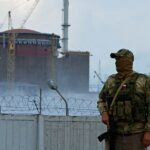 Un militar con una bandera rusa en su uniforme hace guardia cerca de la planta de energía nuclear de Zaporizhzhia.