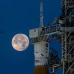 A full moon behind the Space Launch System rocket and Orion spacecraft during testing for the Artemis I mission.