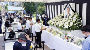 La gente ofrece flores en un puesto instalado en un parque en Tokio el 27 de septiembre de 2022, para presentar sus respetos al asesinado ex primer ministro japonés Shinzo Abe, ya que su funeral de estado tendrá lugar en el cercano salón Nippon Budokan más tarde en el día.  (Kiodo)