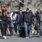 Éxodo: hombres y mujeres rusos con su equipaje caminan por una carretera después de pasar por la aduana en el puesto de control fronterizo entre Georgia y Rusia de Verkhnii Lars, Georgia, el 27 de septiembre de 2022