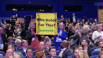 La jefa de asuntos públicos del grupo de campaña Rebecca Newsom (izquierda) y la oficial de políticas Ami McCarthy revelaron la pancarta a mitad del discurso del primer ministro en Birmingham.