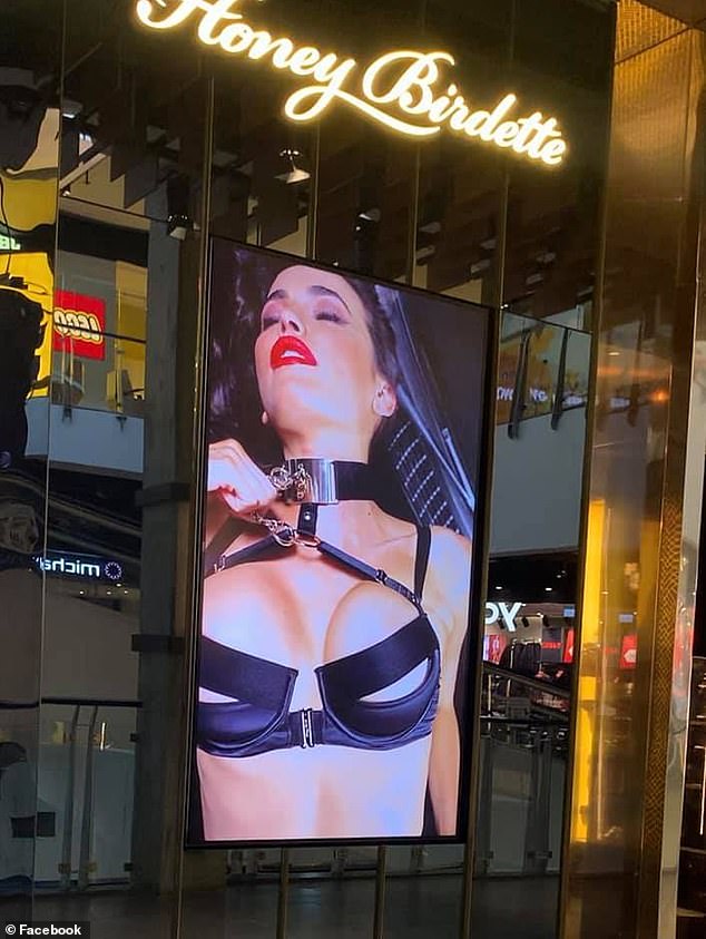 Pantallas gigantes reproducen los controvertidos videoclips de Honey Birdette en los escaparates de las tiendas mientras las familias pasan por el centro comercial Broadway (en la foto)