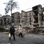 Civiles ucranianos llevan suministros frente a un edificio de apartamentos destruido en la ciudad de Lyman, en el este del país, después de que fuera liberado del control ruso.