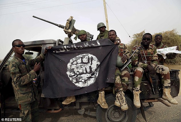 Soldados nigerianos sostienen una bandera de Boko Haram que confiscaron después de retomar la ciudad de Damasak, Nigeria, el 18 de marzo de 2015.