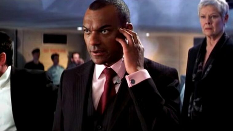 Colin Salmon and Judi Dench stand stoically in a control room in Die Another Day.