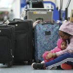 Una pasajera varada sostiene a su hija de 14 meses mientras espera con familiares en la terminal suroeste del Aeropuerto Internacional de Los Ángeles el martes.