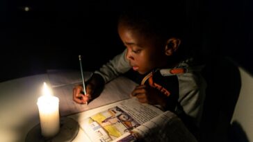A young Zimbabwean boy does his homework by candlelight in Harare.