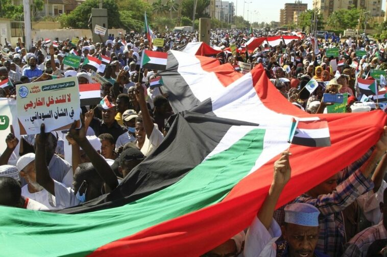Sudanese protesters deploy a giant national flag, as they march outside the UN headquarters in the Manshiya district of the capital Khartoum, on December 3, 2022.