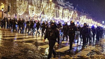 La policía armada usó gases lacrimógenos en las calles de París esta noche después de que estalló el desorden tras la derrota en la Copa del Mundo ante Argentina.  En la imagen: la policía armada marcha por París el domingo
