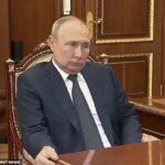 Un Vladimir Putin hinchado e incómodo agarra un escritorio en una reunión con un oficial militar a principios de este año.