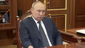 Un Vladimir Putin hinchado e incómodo agarra un escritorio en una reunión con un oficial militar a principios de este año.