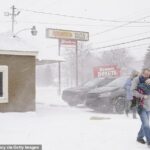 Se ve a una familia corriendo hacia su automóvil en Flint, Michigan, el viernes en medio de condiciones de ventisca.
