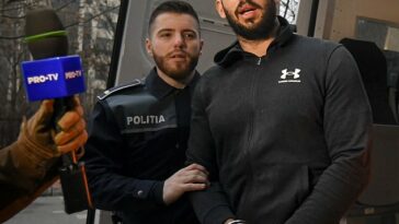 Andrew Tate (en la foto, con un oficial de policía) y su hermano Tristan se quejaron hoy de que las autoridades rumanas están