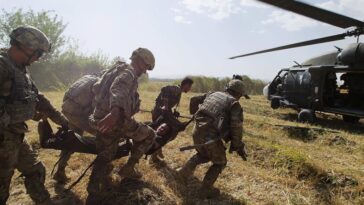 US soldiers carry a wounded person to a helicopter.