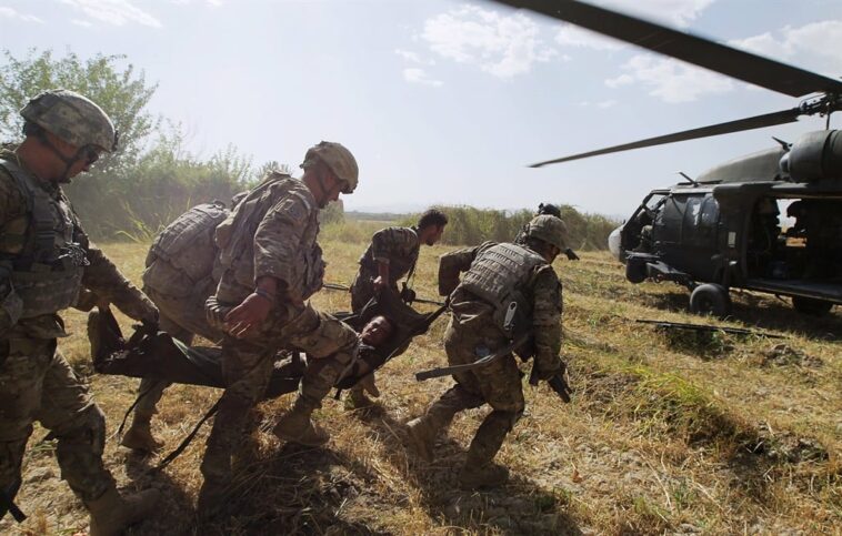 US soldiers carry a wounded person to a helicopter.