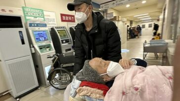 Un paciente anciano es empujado por un pasillo de la sala de emergencias de un hospital en Beijing.